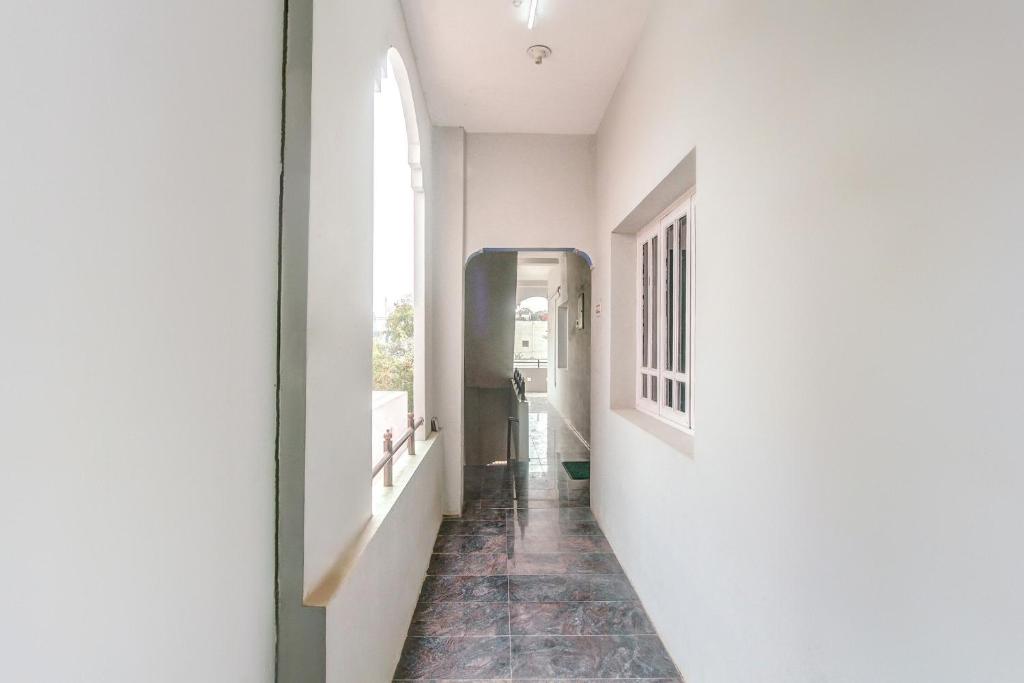 a hallway with a white wall and a window at Hotel O Vivekam Home Stay in Coimbatore