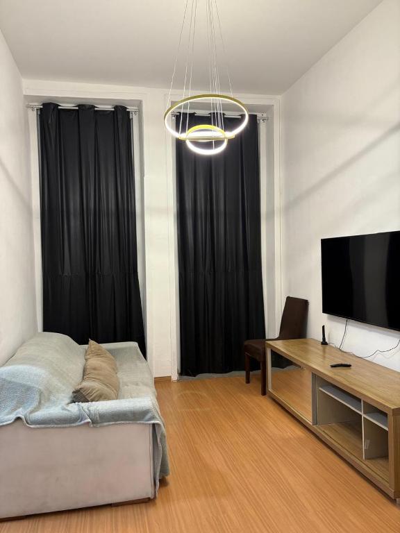 a living room with a bed and a desk and a television at Casarão Maracanã in Rio de Janeiro