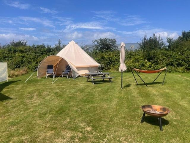 a tent and a chair and a table and a grill at Langø Fjordglamping Telt NR 4 in Nakskov
