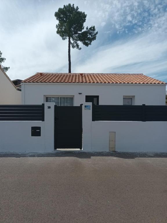 une maison blanche avec un arbre au-dessus dans l'établissement Maison récente Océadune à Saint-Jean de Monts, à Saint-Jean-de-Monts