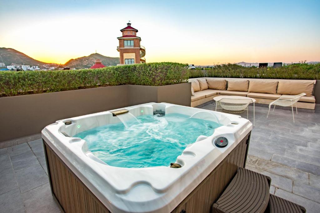 卡波圣卢卡斯Amazing 2 Bdrm condo near medano beach的露台上的热水浴缸，背景是灯塔