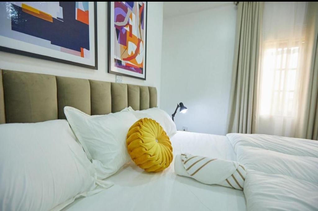 MamaPeridot Apartment Central Area, Abuja的一张白色的床,上面有黄色枕头