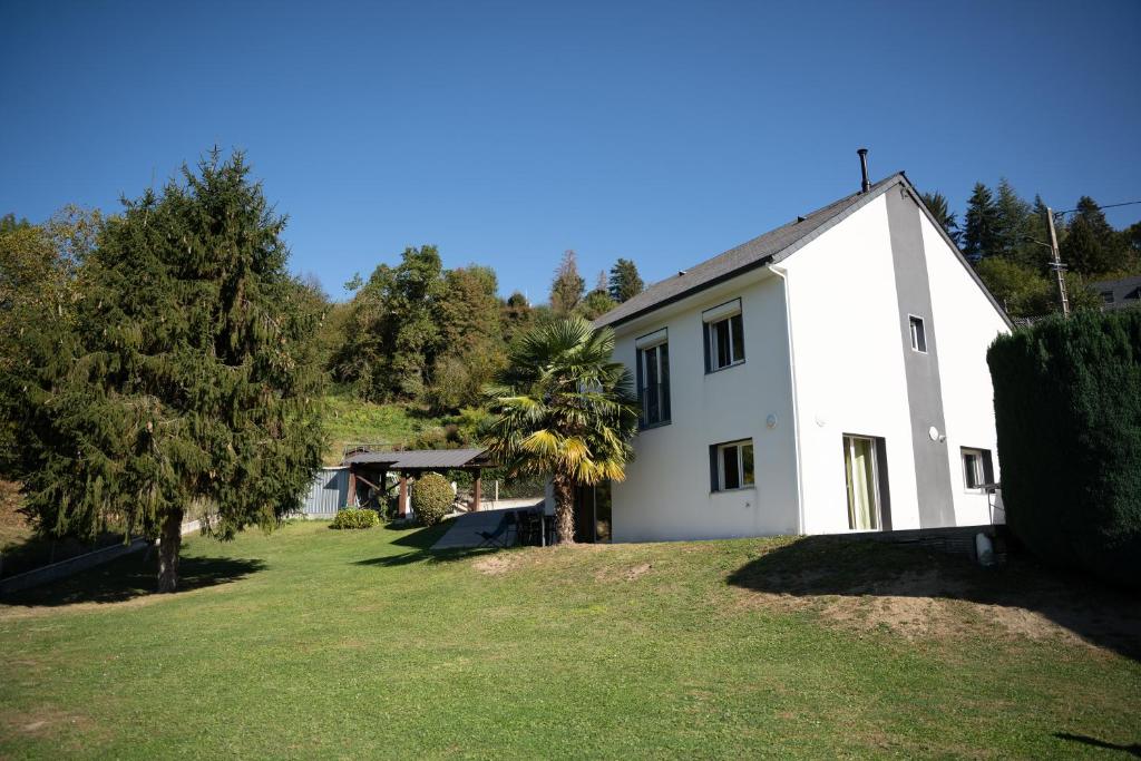 a white house with a grassy yard in front of it at Maison rayons de soleil in Bagnères-de-Bigorre