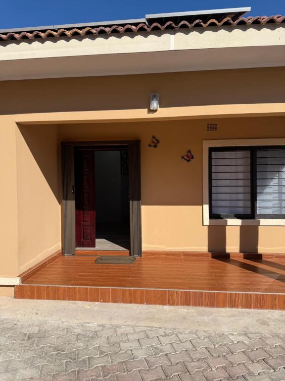 - une porte d'entrée d'une maison avec une terrasse couverte en bois dans l'établissement MY Home Apartments, à Lusaka