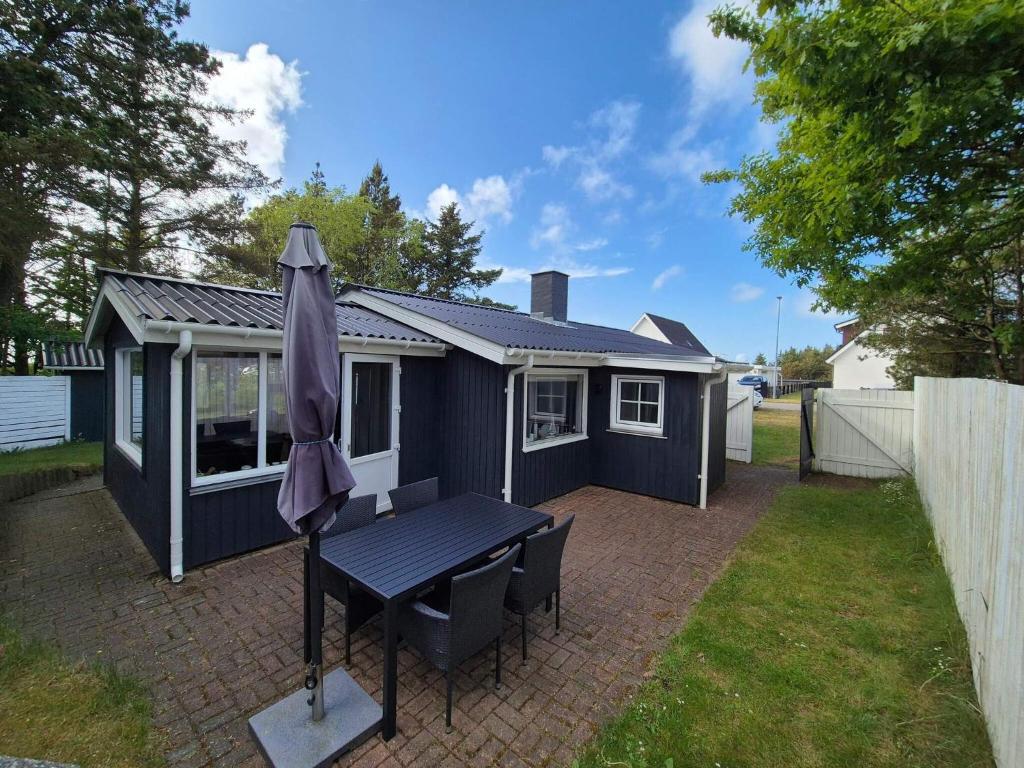 a blue house with a table and an umbrella at 4 person holiday home in Thisted in Thisted