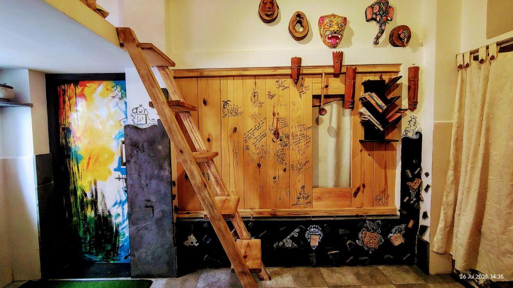 a room with a wooden wall with a ladder at NIRMAN HOMESTAY 5 minutes walk to beach in Puri