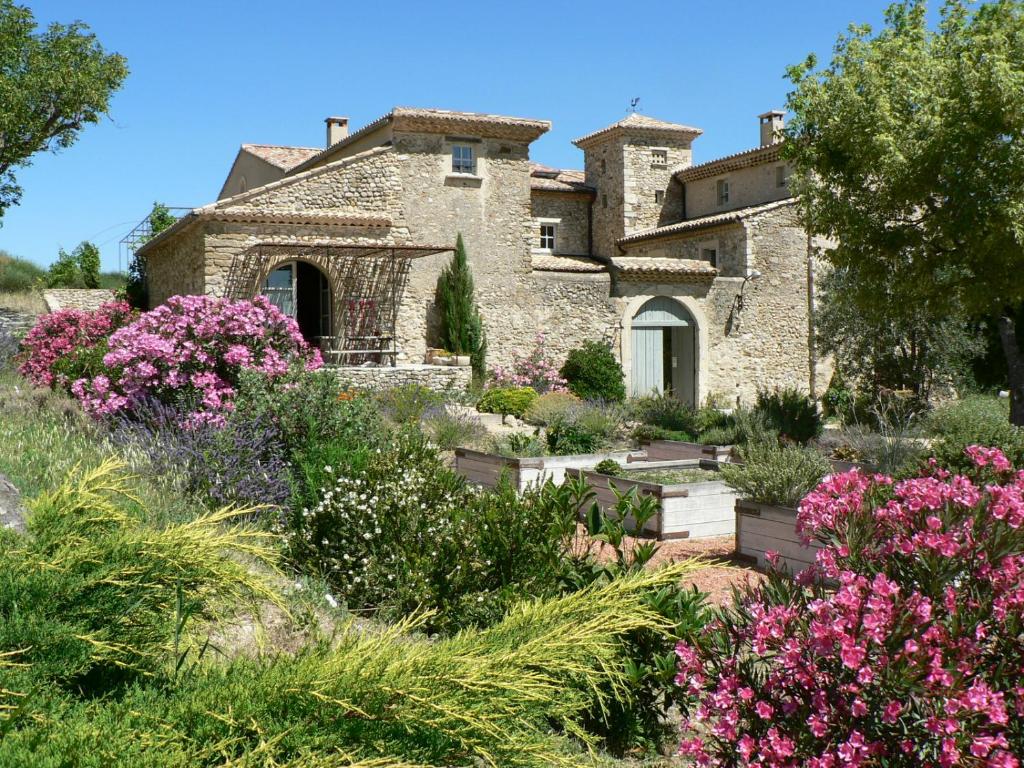 un jardin en face d'une maison en pierre ornée de fleurs dans l'établissement Domaine de Provensol, à Venterol