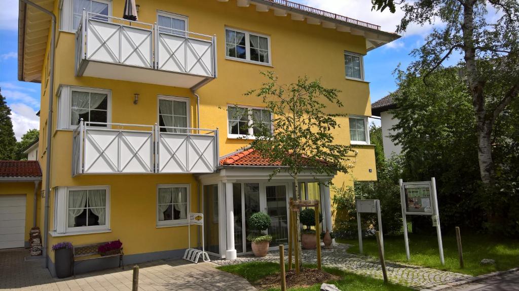 a yellow house with white balconies and trees at Ferienwohnungen Birkenhof in Bad Wörishofen