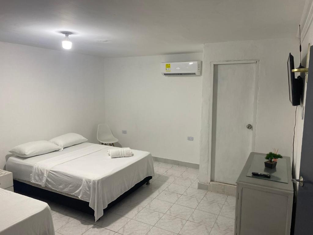 a white room with a bed and a television at Habitación independiente cerca al aeropuerto 1 in Cartagena de Indias