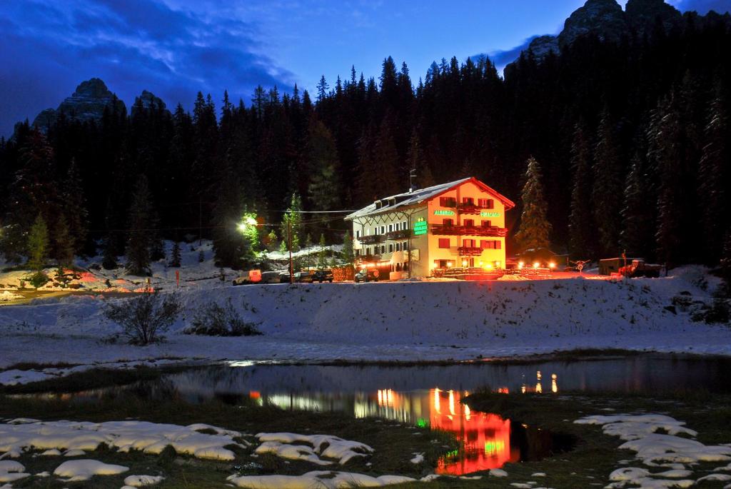 a building in the snow next to a river at night at Hotel Miralago in Misurina