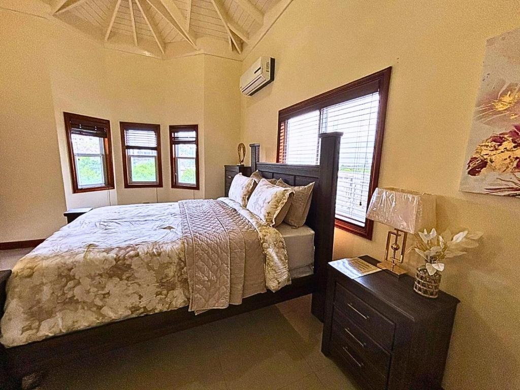 a bedroom with a bed and a dresser and windows at Casa Pors Luxury Apartment with Security, Pool, & Gym in Liguanea