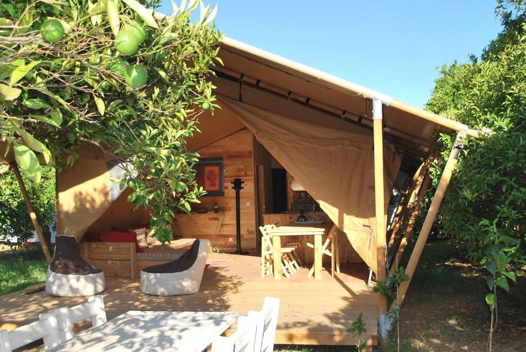 eine Holzterrasse mit einem Zelt im Hof in der Unterkunft Campo Portakal Eco Glamping in Cıralı
