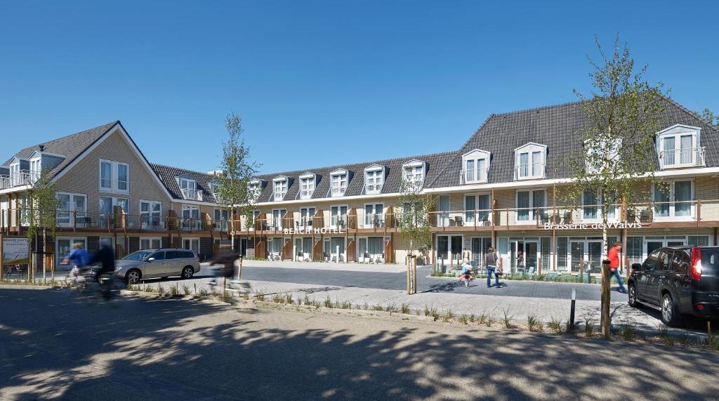 een groot gebouw met auto's geparkeerd voor het bij Beach Hotel I Kloeg Collection in Zoutelande