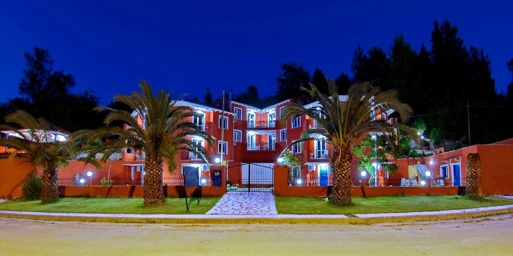 a large red building with palm trees in front of it at Vliho Bay Boutique Hotel in Yénion