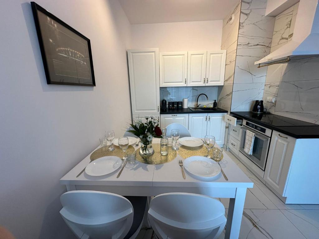 een keuken met een tafel, 2 stoelen en een aanrecht bij GoldClass Apartament in Katowice