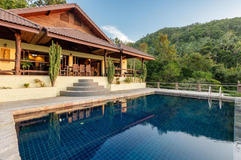 a house with a swimming pool in front of a house at 4 Bedroom villa with stunning sea & sunset view in Haad Yao