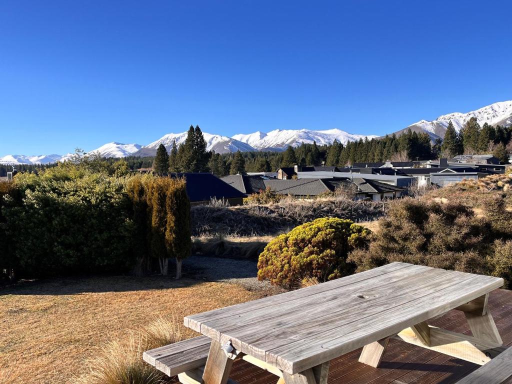 einem hölzernen Picknicktisch auf einem Feld mit Bergen im Hintergrund in der Unterkunft Ashley's Retreat - Lake Tekapo in Lake Tekapo