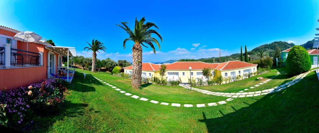 a yard with a palm tree and a house at Arion Hotel in Kokkari