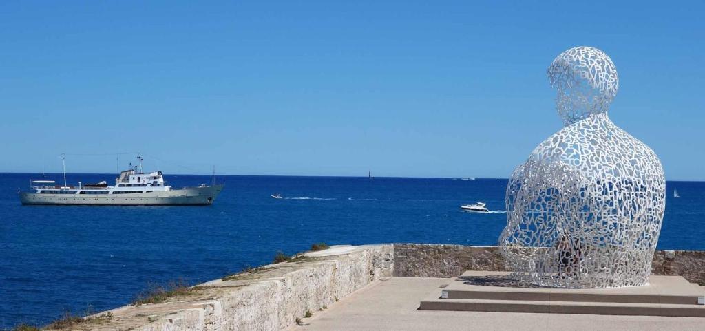 une statue d'un homme regardant un bateau dans l'eau dans l'établissement JULIUS 6 couchages, parking privé, à Antibes