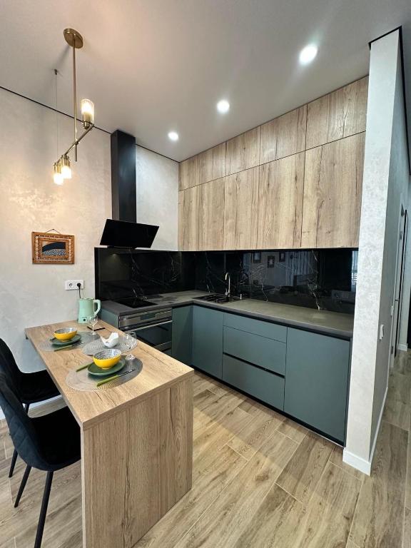 a kitchen with blue cabinets and a wooden table at Atmosfera Sea View Apartments in Odesa