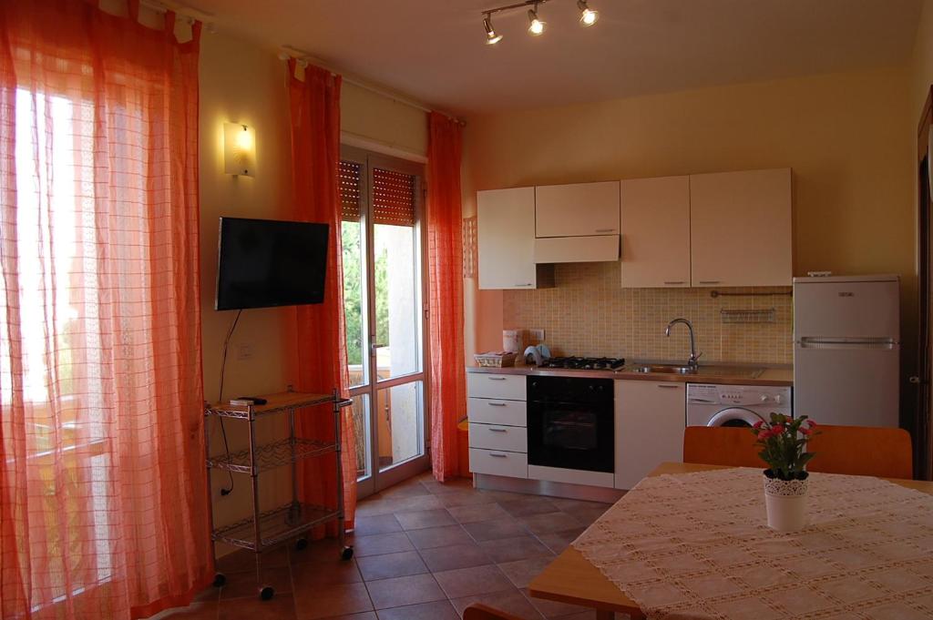 ガリポリにあるTramonto -Appartamenti OltreMare- Lido Conchiglie Gallipoliのキッチン(オレンジ色のカーテン、テーブル、テーブル付)