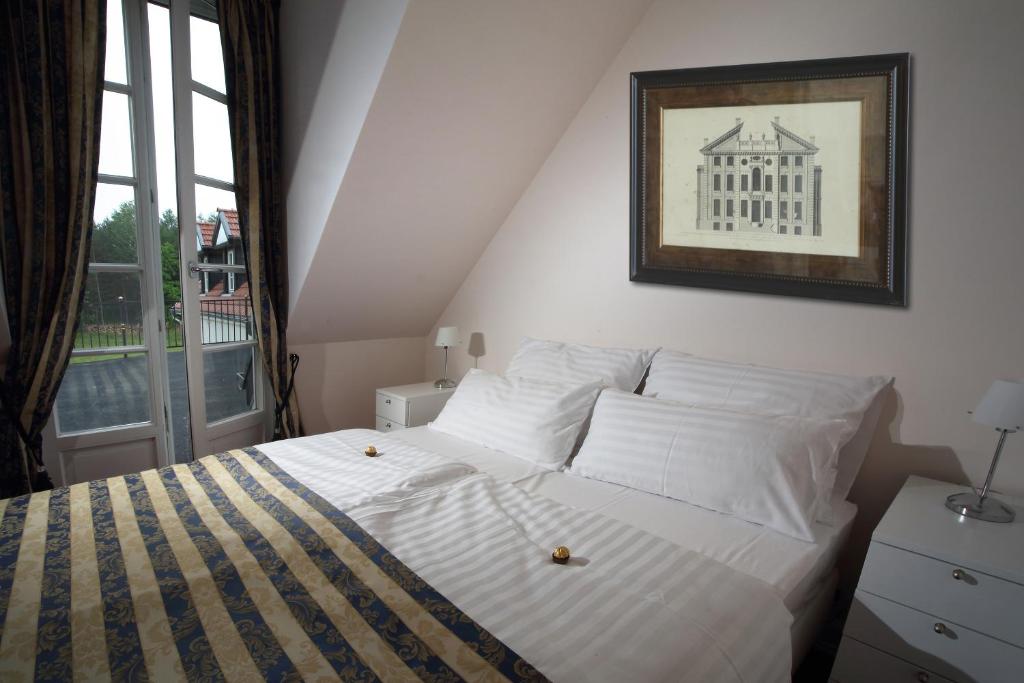 Cozy attic double bedroom with striped bedding, bedside tables and framed architectural print.