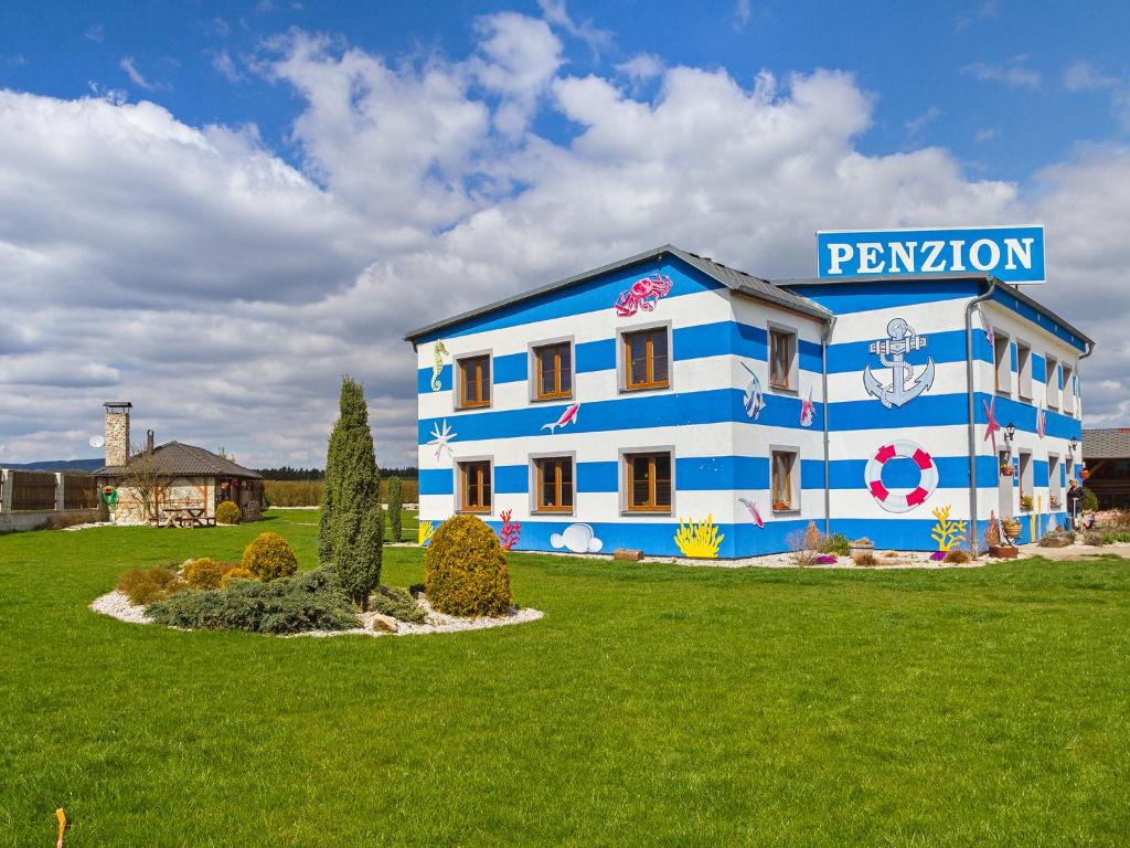 a blue and white building in a green field at Penzion U Námořníka in Františkovy Lázně