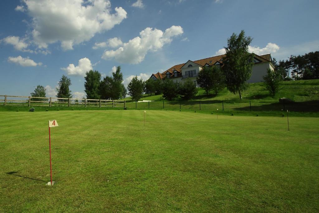 Well-kept putting green marked with flag number four, hotel building visible on grassy hill.