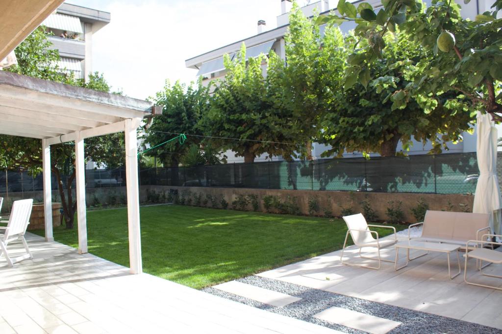 a patio with white chairs and a yard with grass at Giorgia's House in Silvi Marina