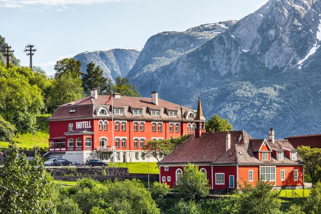 a large red house in front of a mountain at Tyssedal Hotel in Tyssedal