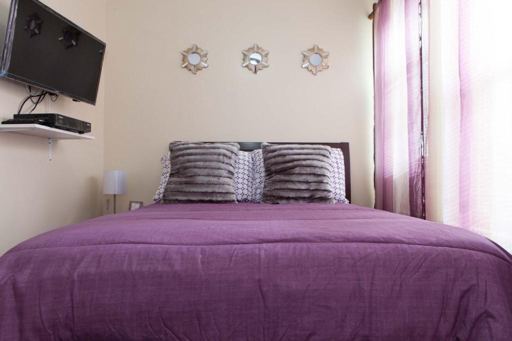 a bedroom with a purple bed with a tv on the wall at Studio, One and Two Bedroom Apartments - Bronx in Bronx