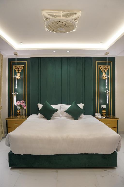 a bedroom with a large white bed with green walls at Dimora Hotel Anarkali in Lahore