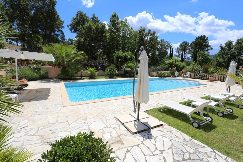 una piscina con due ombrelloni e due sedie a sdraio e una piscina di Lou Relambi a Bagnols-en-Forêt