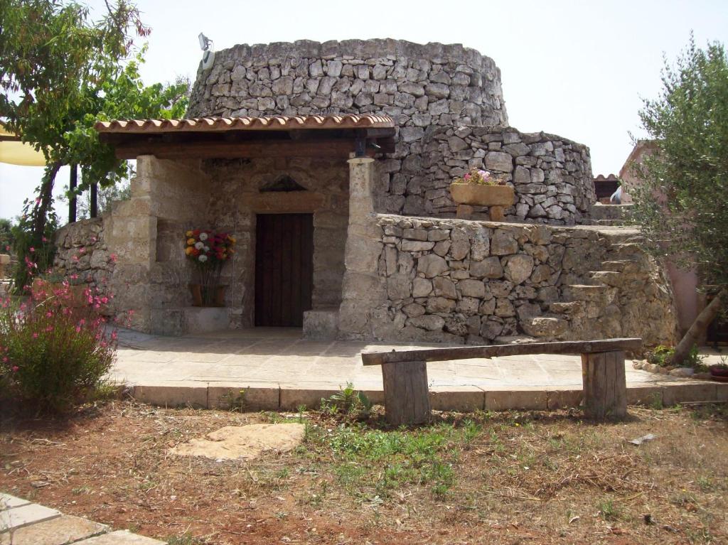 ein Steingebäude mit einer Bank davor in der Unterkunft Trullo Contrada Stracca in Alliste