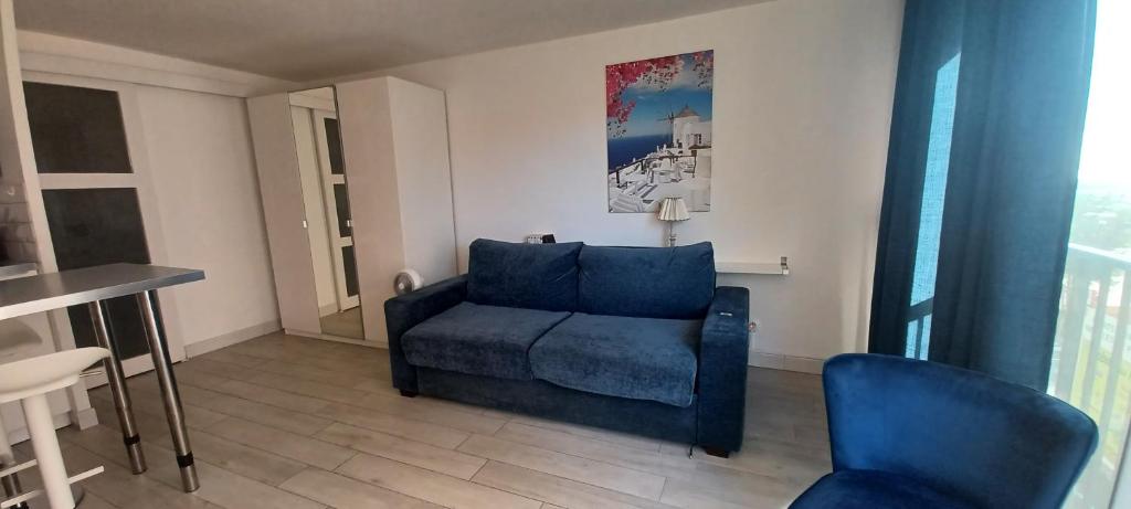 un salon avec une chaise bleue et une table dans l'établissement Appartement bord de mer le Capitaine, à Valras-Plage