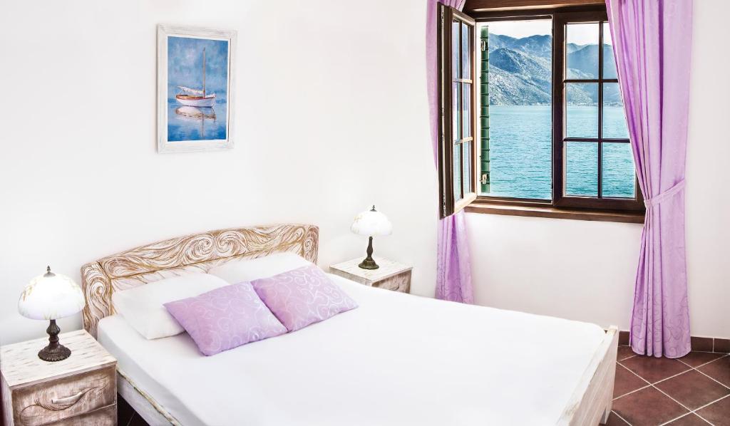 a white bedroom with a bed and a window at Apartments Boka Vista in Kamenari