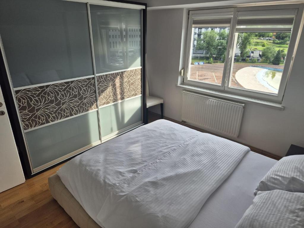 a bedroom with a white bed and a window at Stan apartman Ilidza in Sarajevo