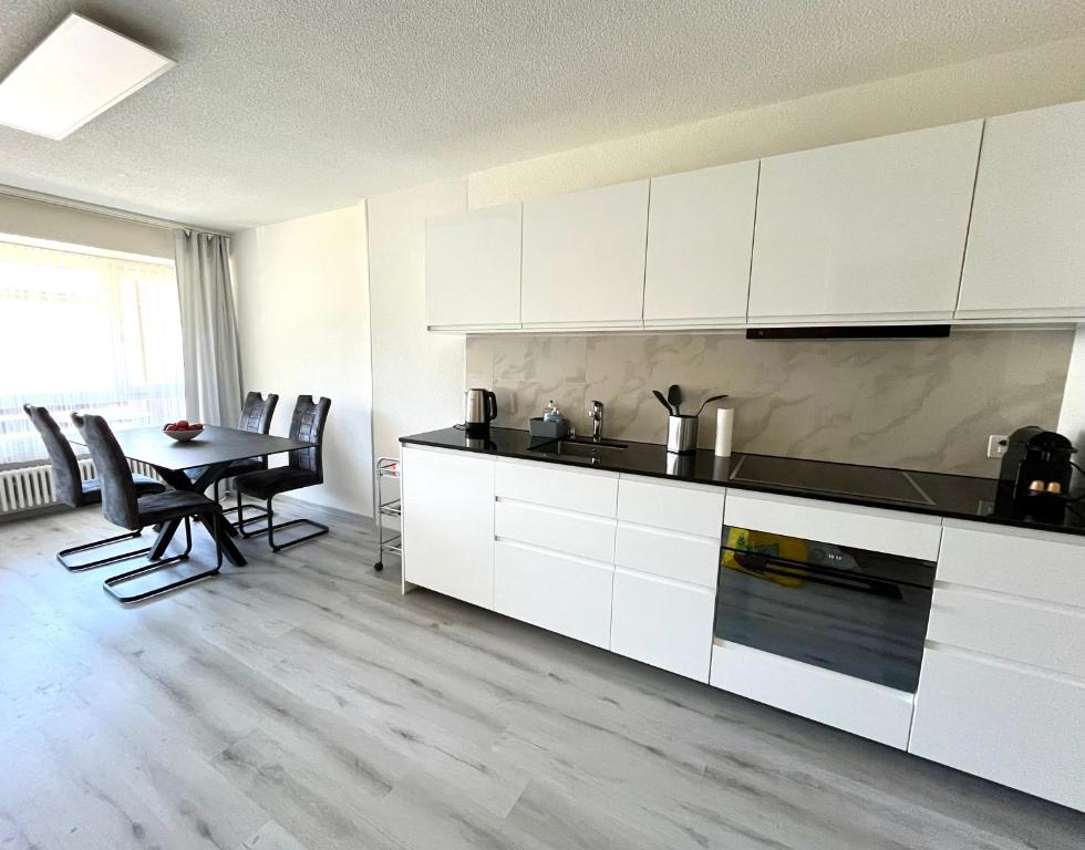 a kitchen with white cabinets and a table with chairs at Family friendly duplex with free parking in Leukerbad