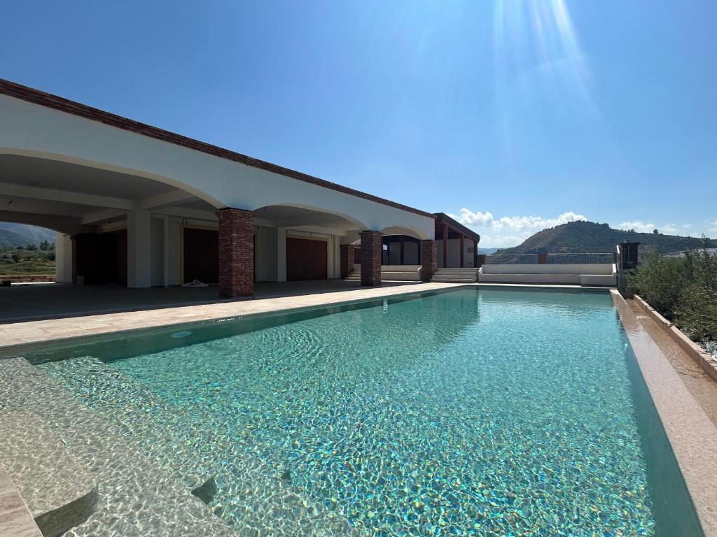 a swimming pool with blue water in a building at Chalet Tenuta Lacco in Furnari