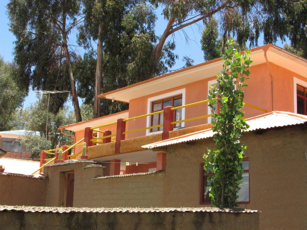 ein orangefarbenes Haus mit Balkon darüber in der Unterkunft Titicaca Chaska Wasi Amantani in Ocosuyo