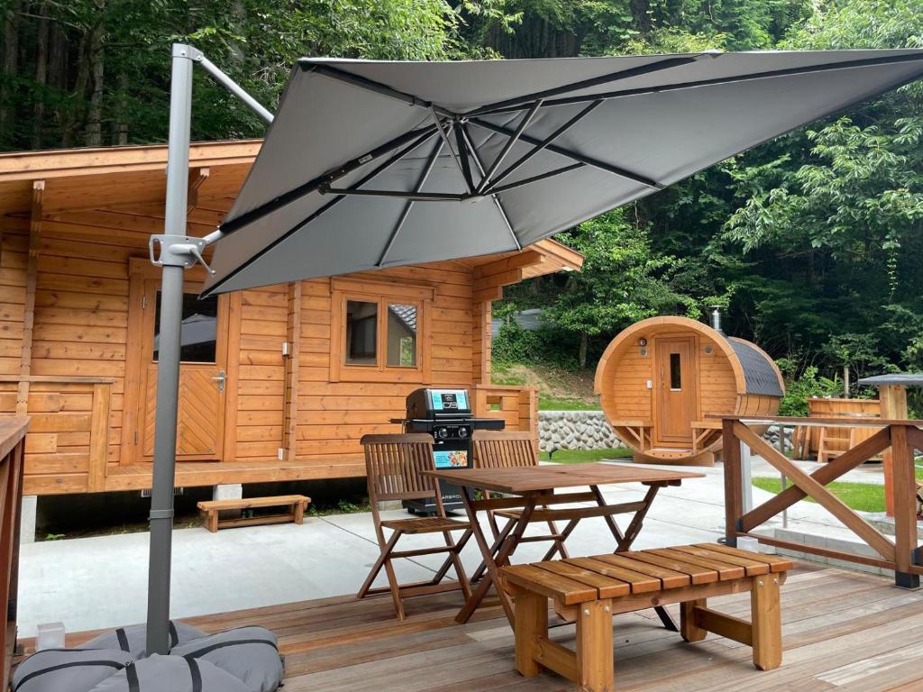 a large black umbrella on a deck in front of a cabin at Kanoto DE Sauna in Motojuku