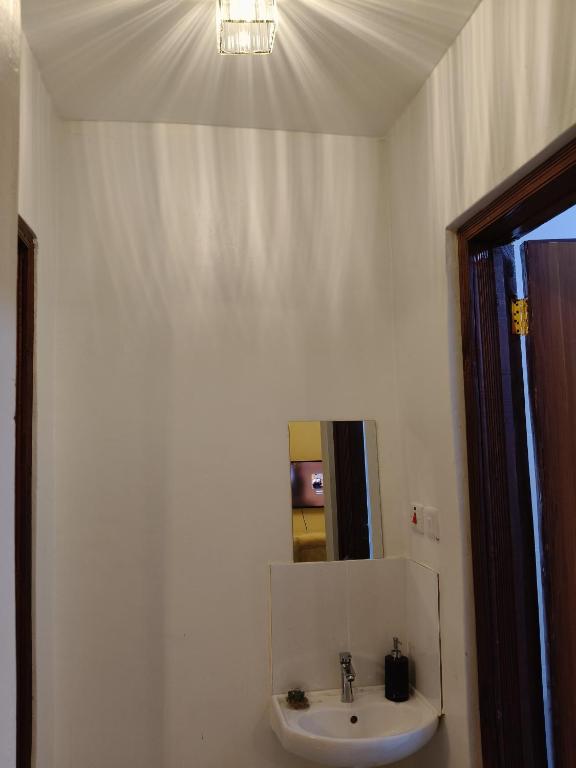 a white bathroom with a sink and a mirror at Homely Homes in Eldoret