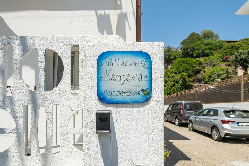 a sign on a building with cars parked in a parking lot at Monolocale Marizzola in Cala Gonone