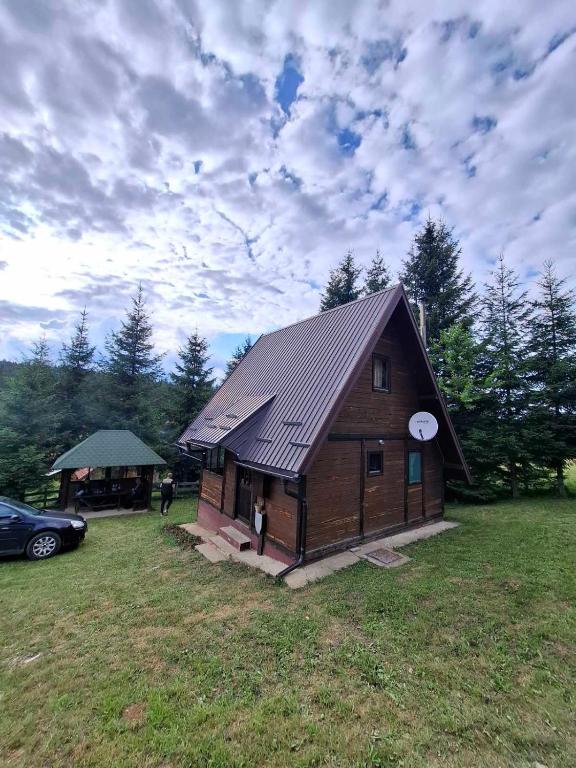 una pequeña cabaña en un campo con coche en Planinska kuca Beli bor, en Jokići