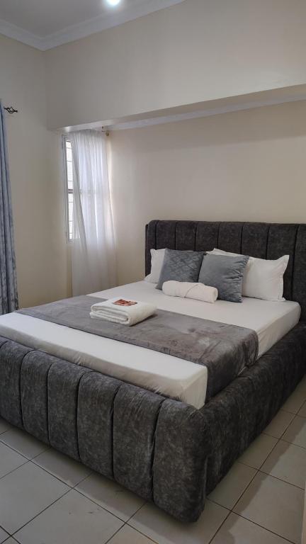 Una cama grande en una habitación blanca con una falda de cama grande. en Lauryl Comfy Stays, en Kisumu