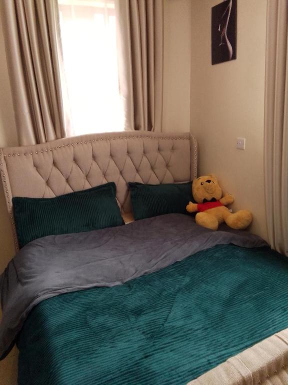 a teddy bear sitting on top of a bed at Stays with Fred in Ruiru
