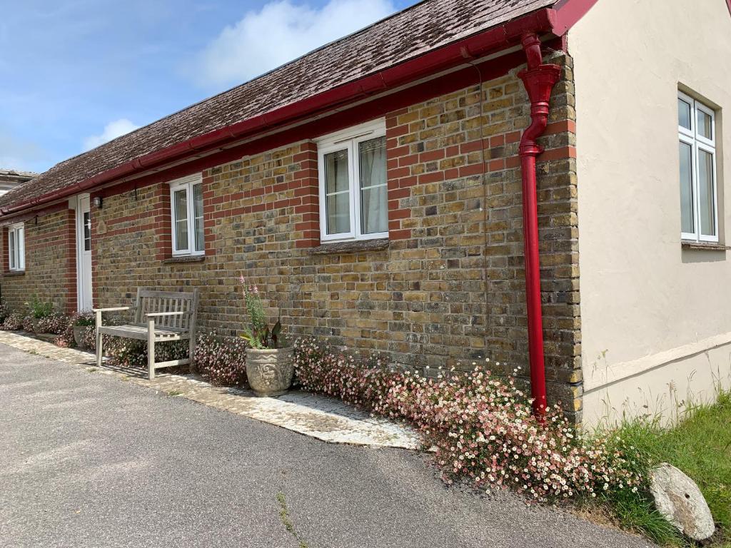 ein Backsteingebäude mit einer Bank neben einer Straße in der Unterkunft Old School Cottage in Toller Porcorum