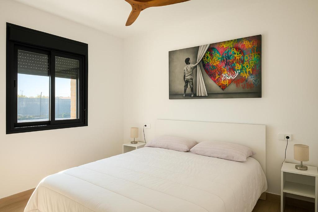 une chambre avec un lit blanc et un tableau au mur dans l'établissement Casa Lucas&Cloe - Refuge Between Marshlands and Sea, à Barbate