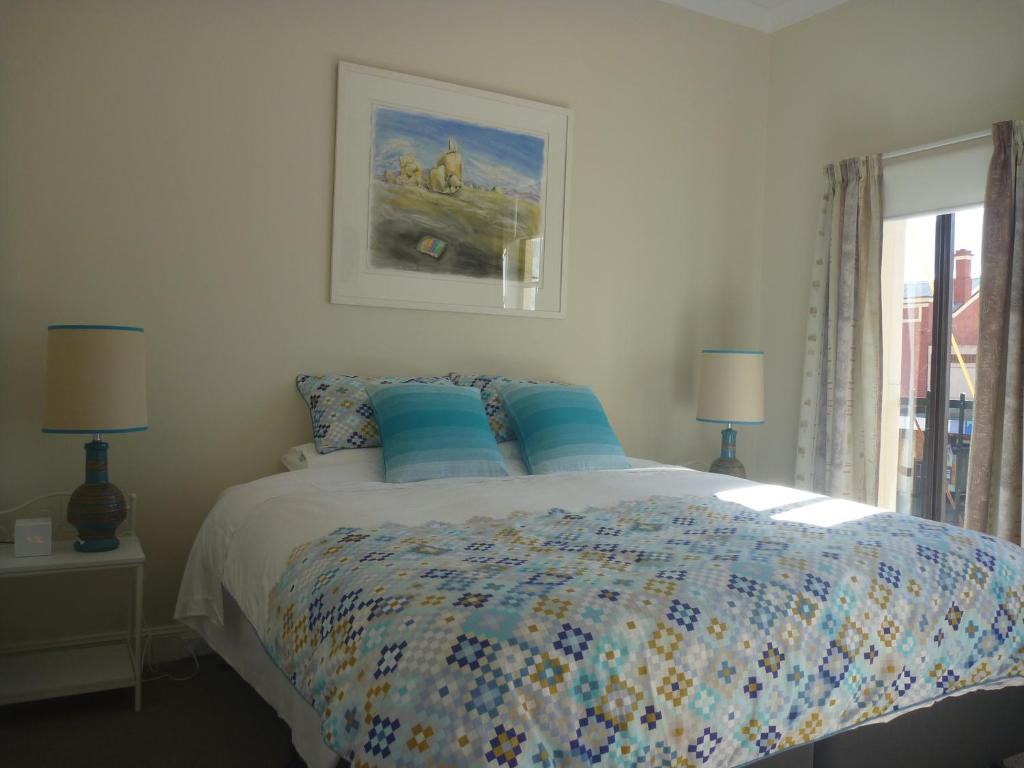 a bedroom with a bed with blue pillows and a window at Apartments On Grey in Glen Innes