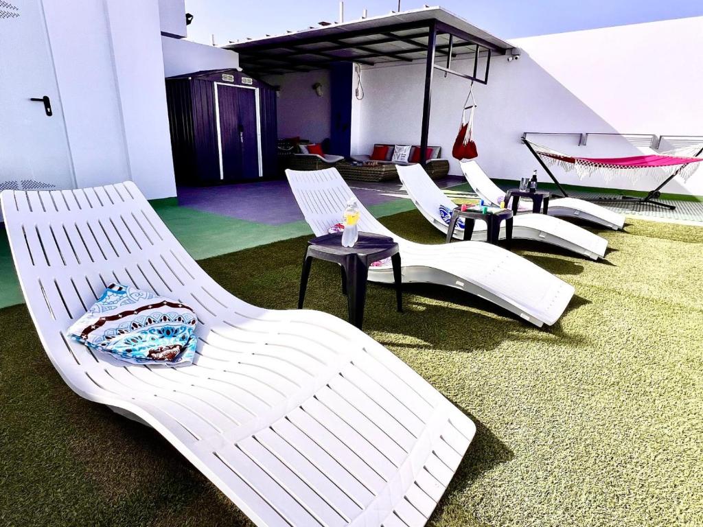 a group of white chairs in a room with a hammock at ANIMOSS! APARTMENTS - 10 modern apartments near city center & beach in Santa Maria